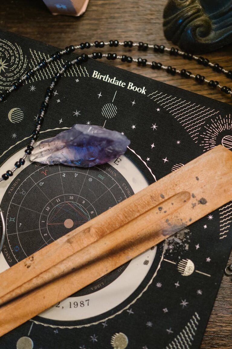 Astrology-themed flat lay featuring a birthdate book, crystals, and necklace on a wooden surface.